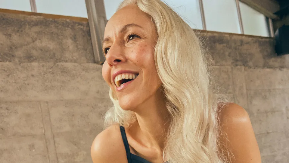 Fit and healthy woman with long blonde hair looking happy.